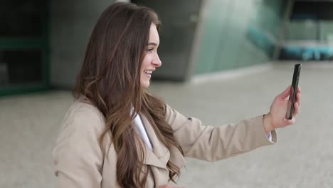 Woman-having-video-chat-on-phone-outside,-waving-hand,-smiling